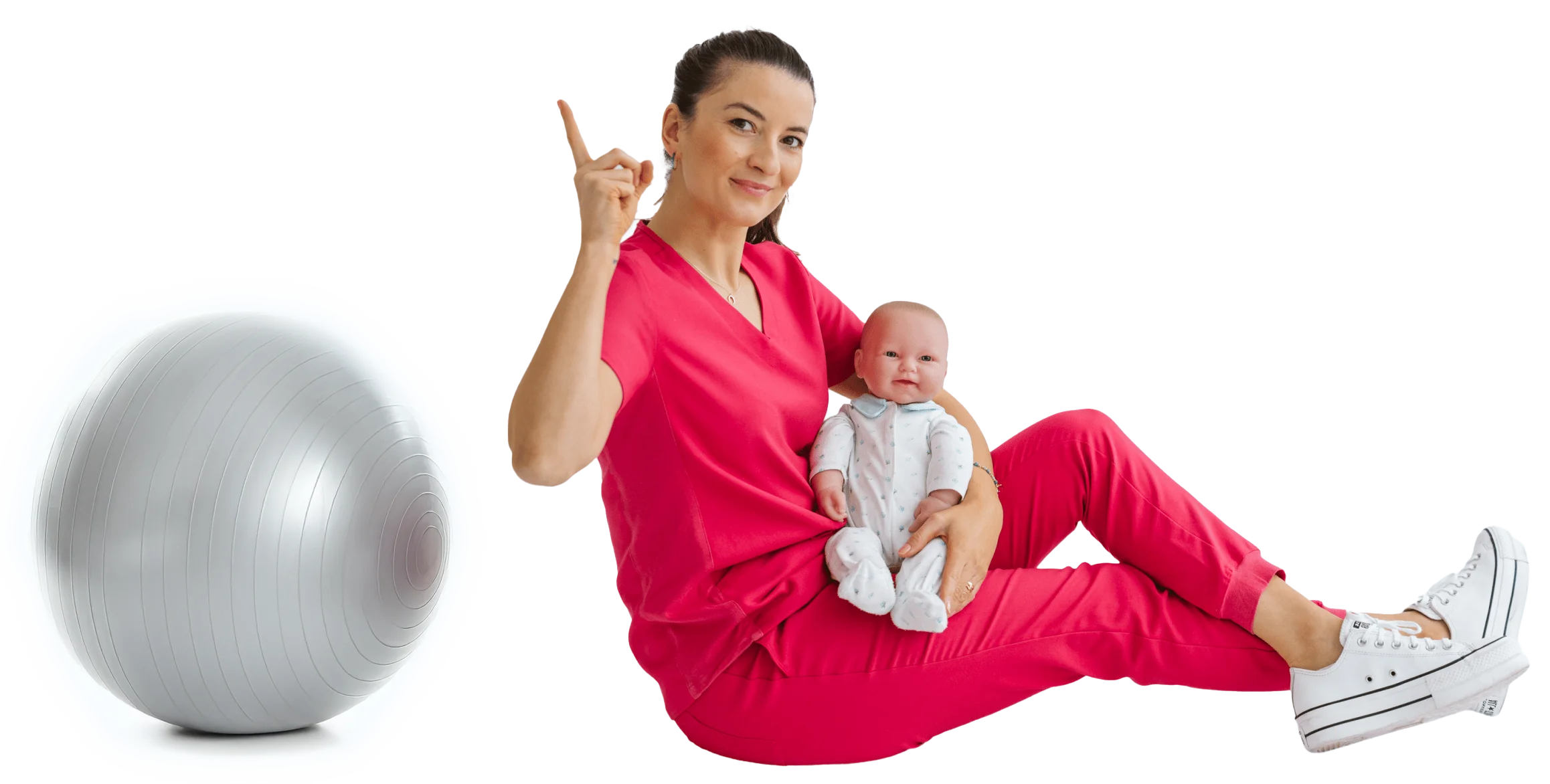 Izabella Malara-Zygaj w różowym uniformie medycznym siedzi na podłodze z lalką niemowlęcia na kolanach, unosząc palec wskazujący do góry; obok piłka gimnastyczna.